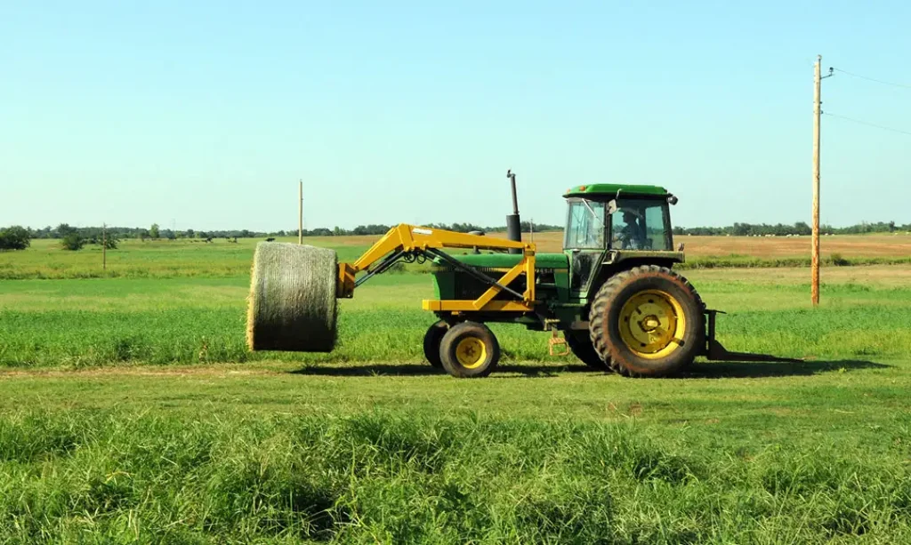Steve Burris moves hay bales on his farm in McLoud