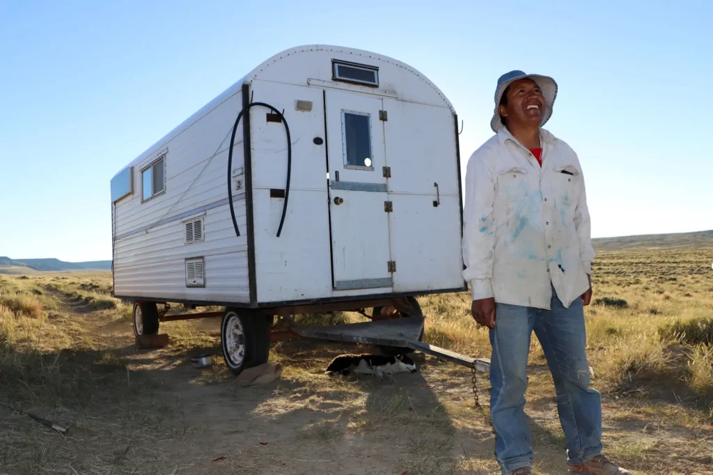 A sheepherder in Utah stands outside his mobile housing unit