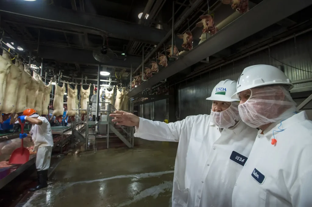 A U.S. Department of Agriculture (USDA) inspector shows Agriculture Secretary Sonny Perdue around the processing floor of the Triumph Foods St. Joseph