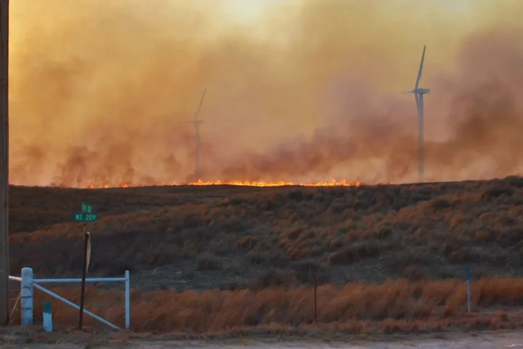 Flames from the 34 Complex Fire rage near a wind turbine site approximately 7 miles north of Woodward